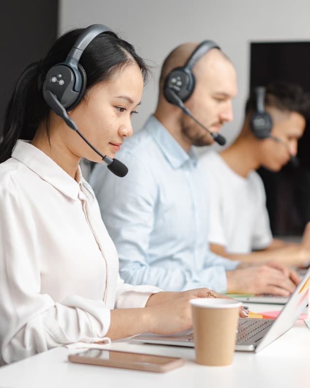 Contact-Center-Mitarbeitende mit Headsets an Laptops